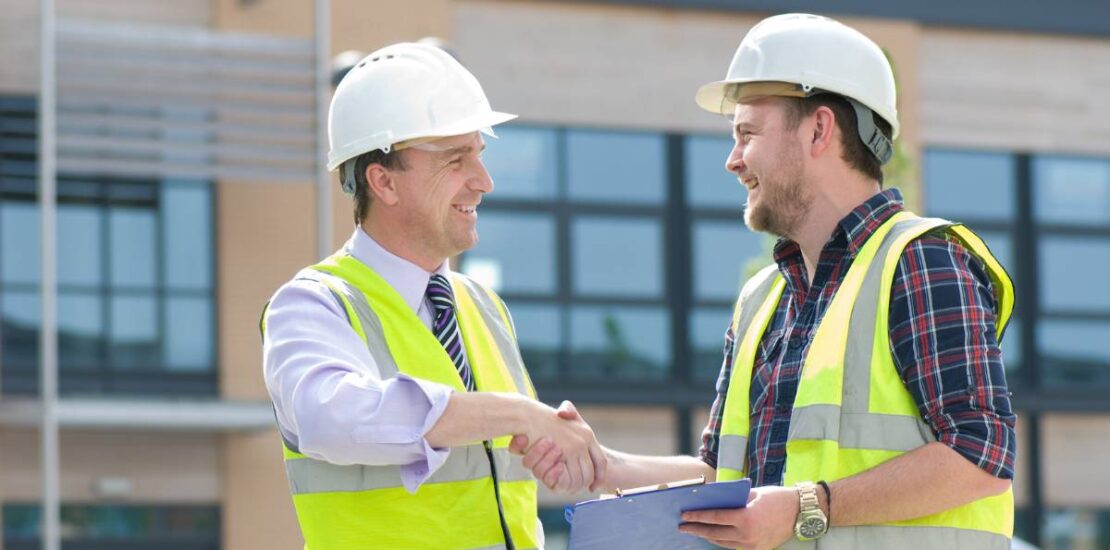 Contractors at a construction site using digital tools to manage the project and collaborate.