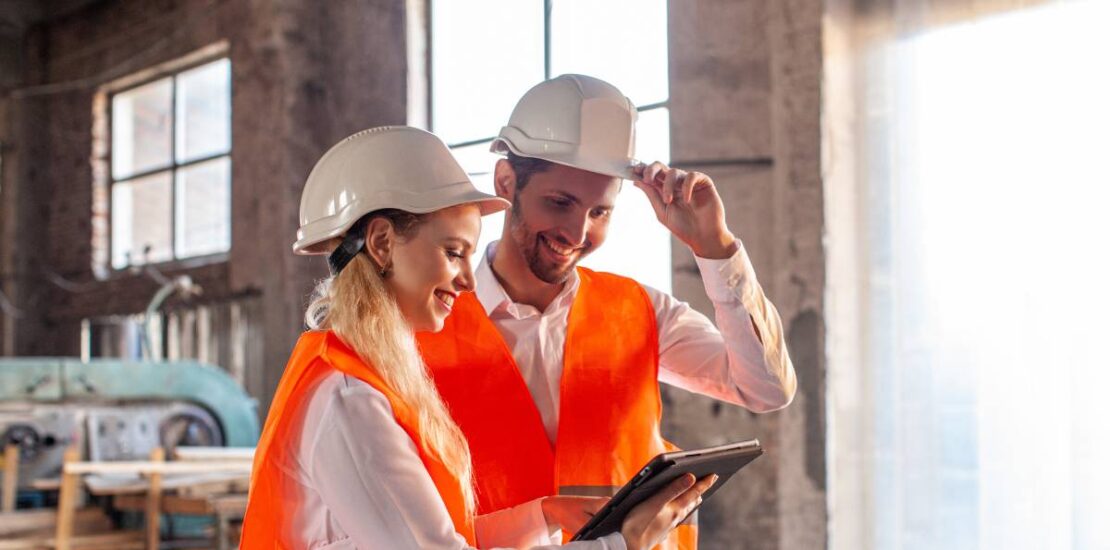 Construction professionals discussing plans on-site, symbolising recruitment and teamwork.