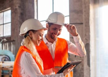 Construction professionals discussing plans on-site, symbolising recruitment and teamwork.